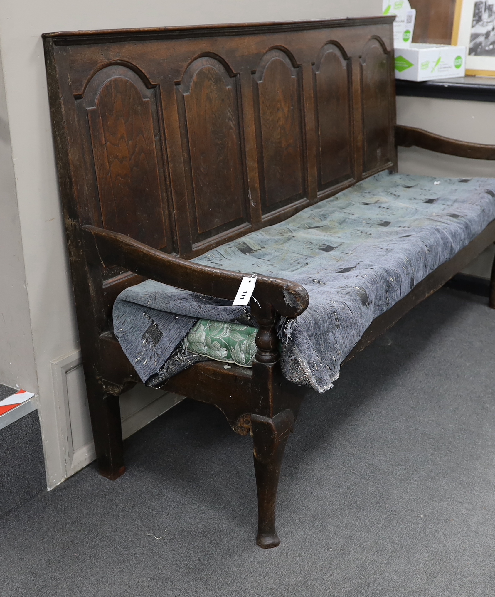 An 18th century panelled oak settle, with squab cushion seat, width 184cm, depth 65cm, height 112cm